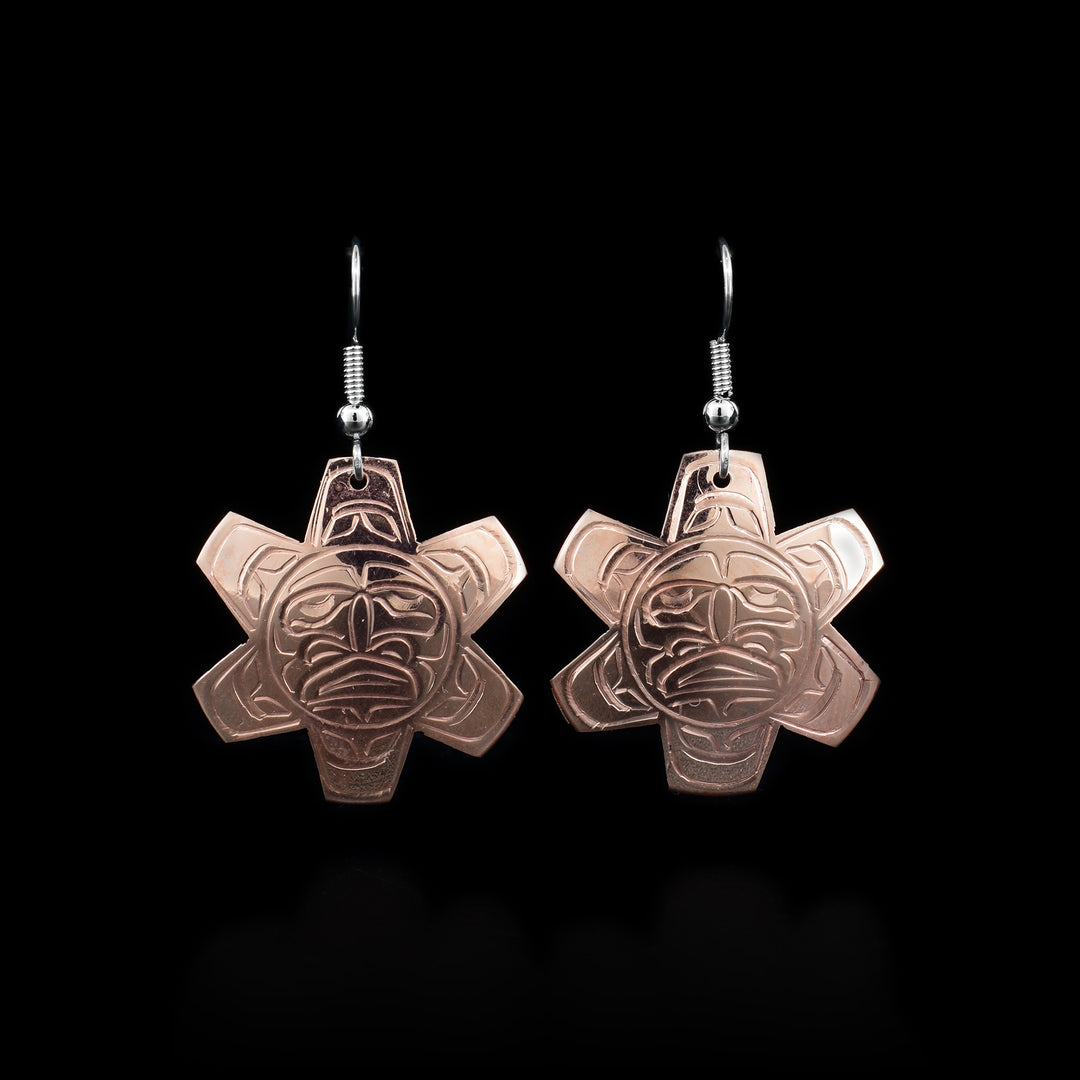 These copper dangle earrings have hangs that are shaped like and have carvings on the surface of it that depict the Sun.