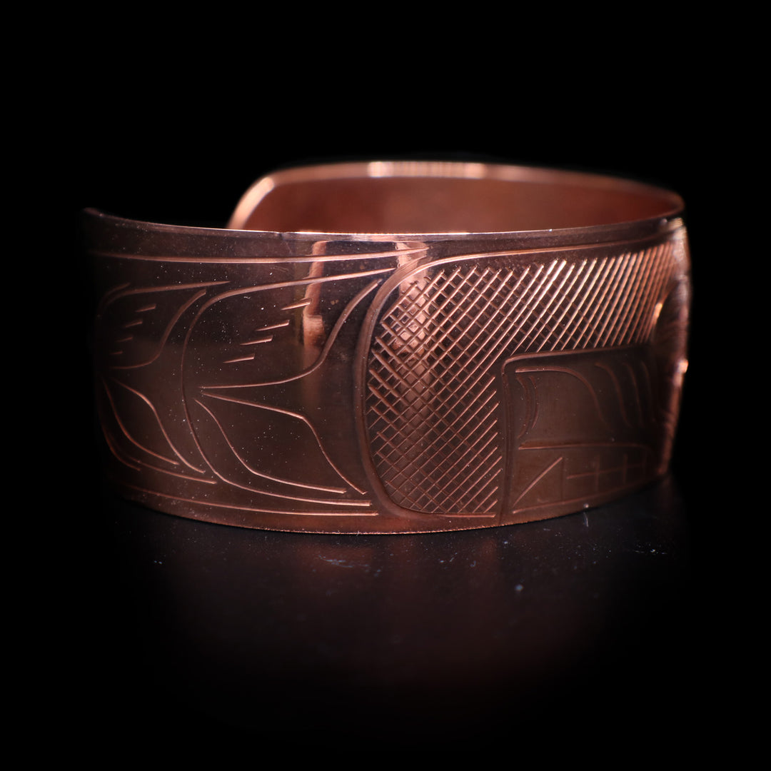 This wide cuff bracelet has a single copper band with a gap in the back. There is a full depiction of the Wolf legend carved across the surface of the band.