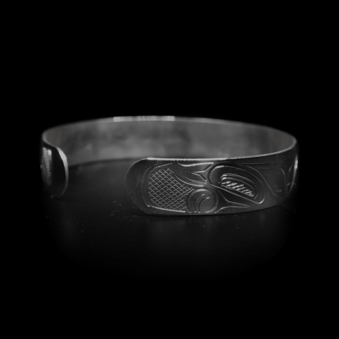This large Bear bracelet cuff has a sterling silver band with a gap in the back. There are two depictions of the Bear carved into the band. The heads meet in the center of the band and their bodies are depicted on either side of the band.