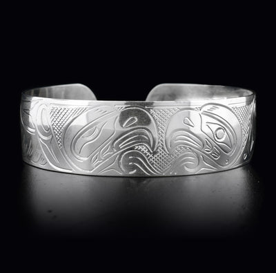 This sterling silver cuff bracelet has a wide band with two depictions of the Eagle carved into it. Their heads meet at the top of the bracelet.