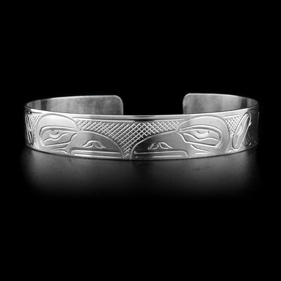 This sterling silver cuff bracelet has two depictions of the Raven carved into it. Their heads meet at the top of the bracelet.