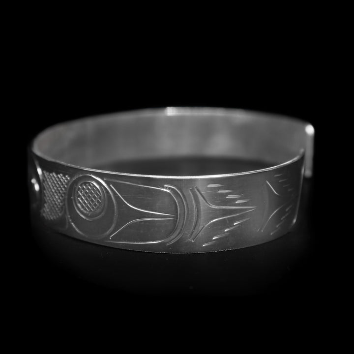 This large Eagle bracelet cuff ahs a sterling silver band with a gap in the back. there are depictions of the Eagle legend facing each other carved into the band.