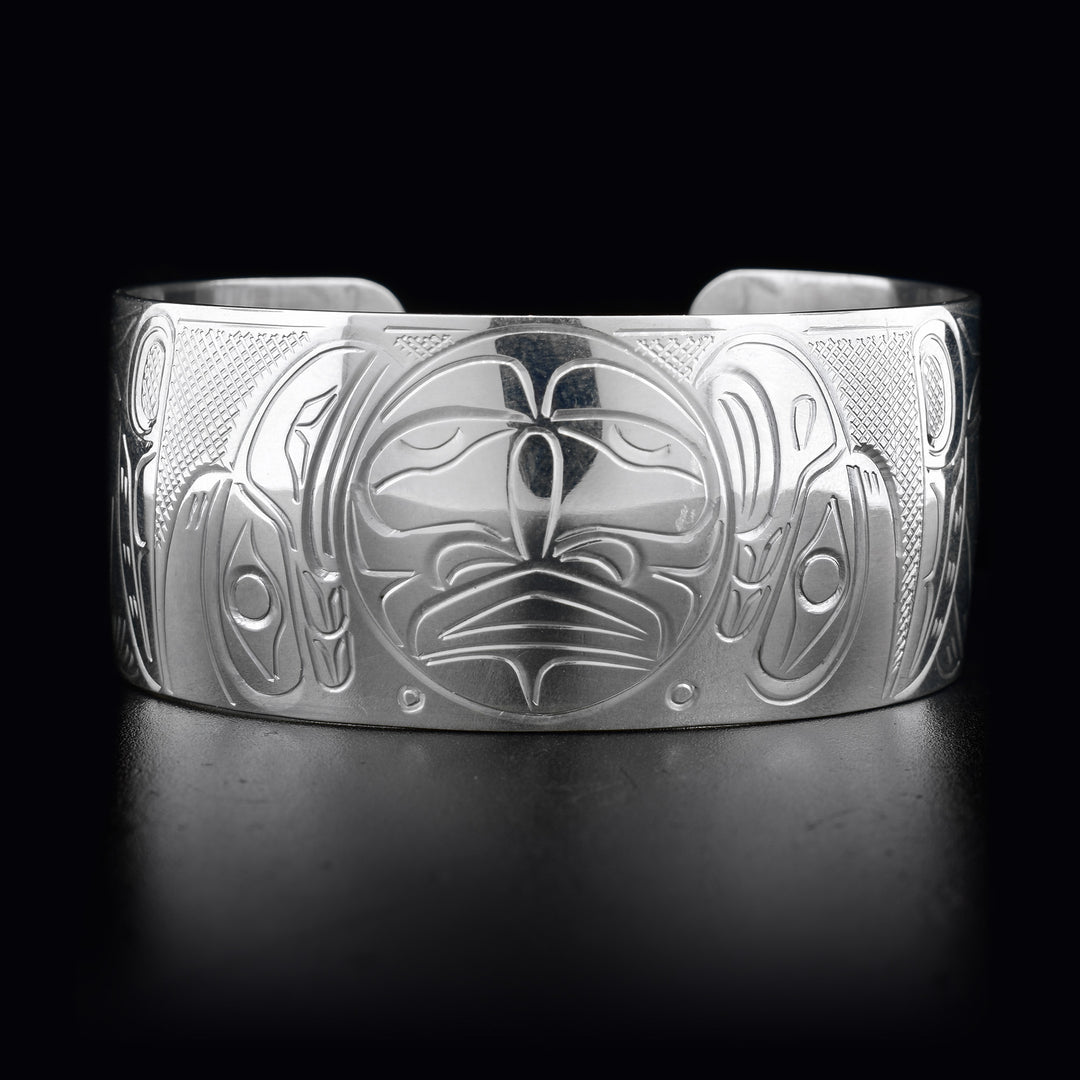This wide cuff bracelet has a large band with depcitions of the Eagle, the Raven, and the Moon carved into it. The Moon is in the center of the bracelet with the Eagle and the Raven on either side.