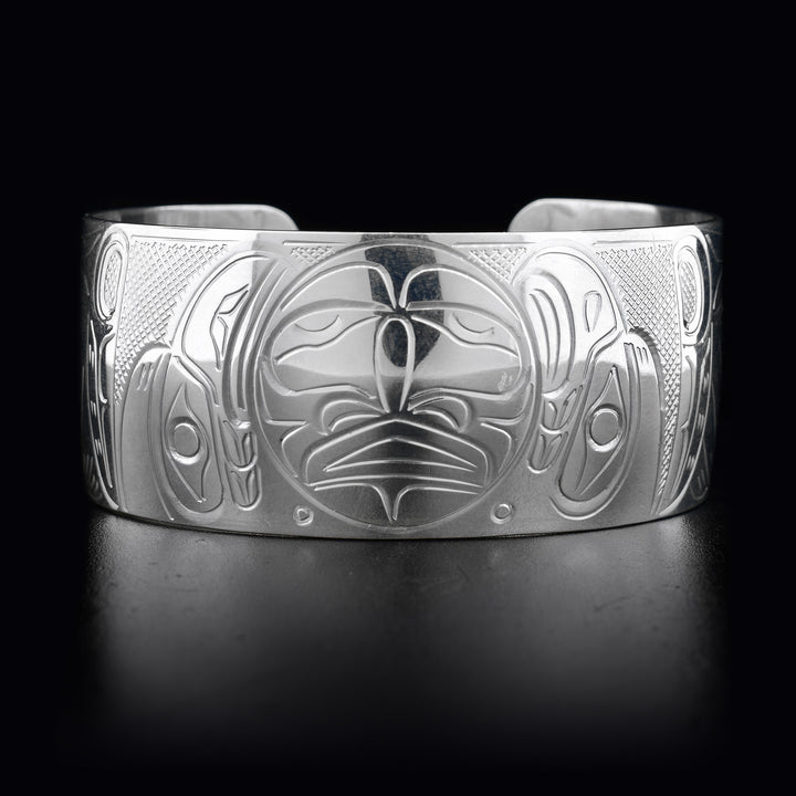 This wide cuff bracelet has a large band with depcitions of the Eagle, the Raven, and the Moon carved into it. The Moon is in the center of the bracelet with the Eagle and the Raven on either side.