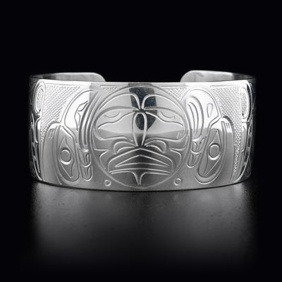 This sterling silver cuff bracelet has a large band with depcitions of the Eagle, the Raven, and the Moon carved into it. The Moon is in the center of the bracelet with the Eagle and the Raven on either side.