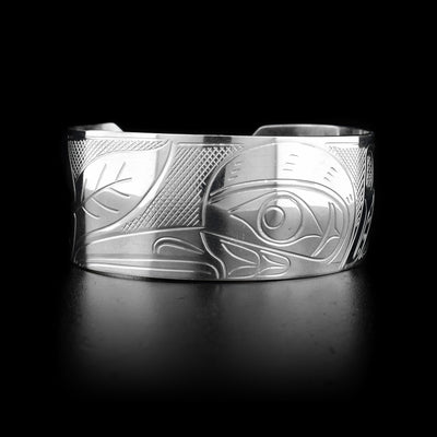This sterling silver cuff bracelet has a wide band with a flower and a depiction of the Hummingbird carved into it. 