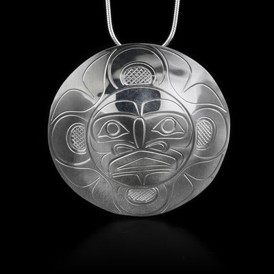 This large, sterling silver pendant is circle shaped and has carvings that depict the Moon on it.