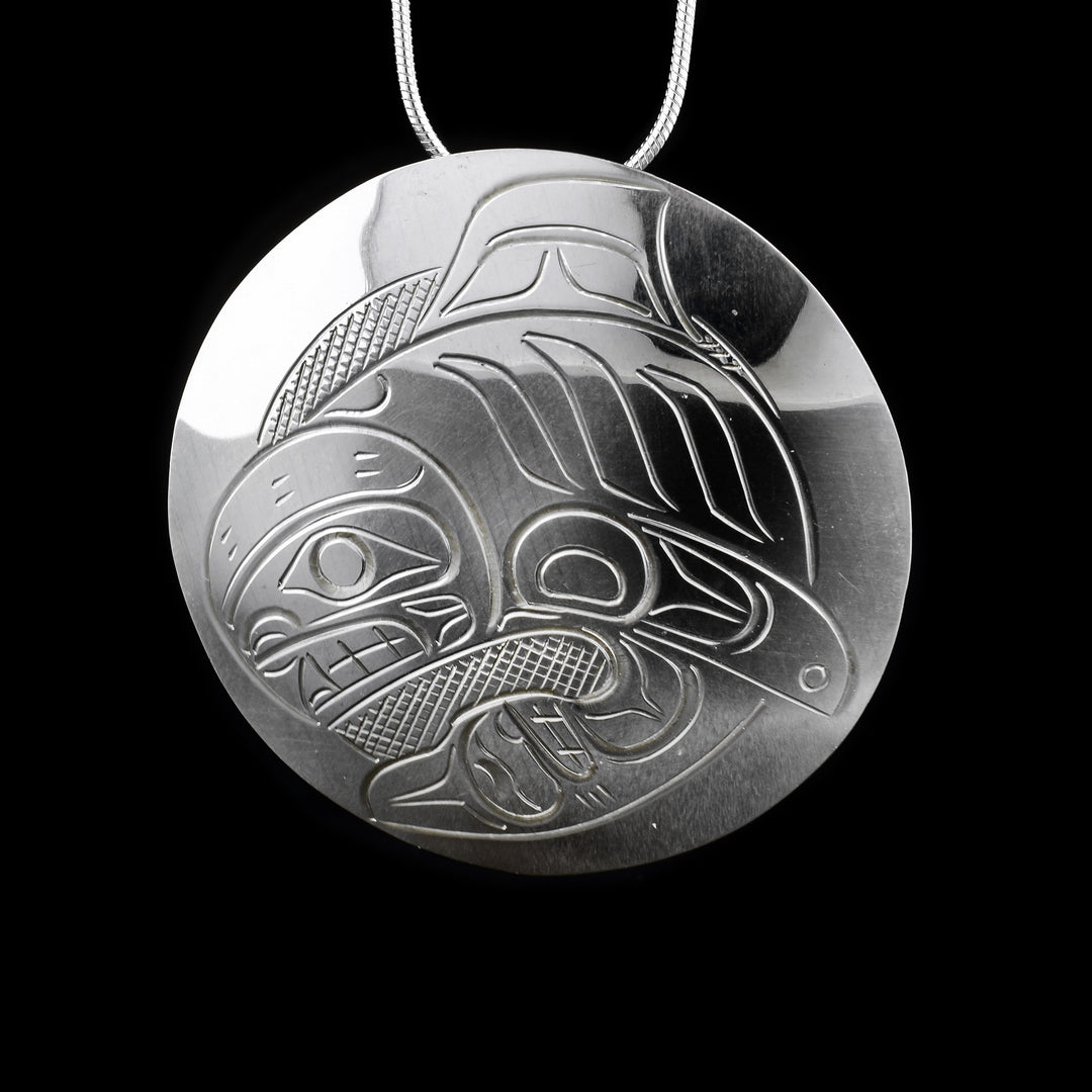 This sterling silver pendant is circle shaped and has a depiction of the Orca carved into it.