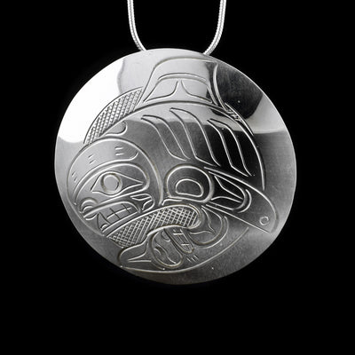 This stelring silver pendant is circle shaped and has a depiction of the Orca carved into it.