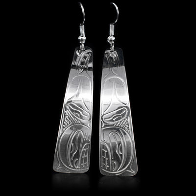 These sterling silver earrings have long, thin hangs that curve in slightly. There is a depiction of the orca carved into them.