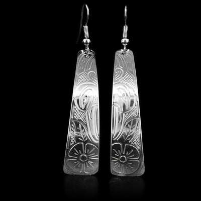 These sterling silver earrings have hooks which have triangular hangs attached to them. The hangs are long and curved inside slightly in the bottom. The Hummingbird's face is depicted on the hangs, as well as a flower underneath. The Hummingbird is facing downwards.