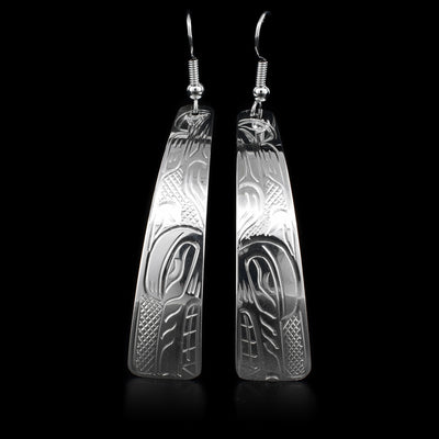 These sterling silver dangle earrings have long hangs with a depiction of the Wolf carved into them.