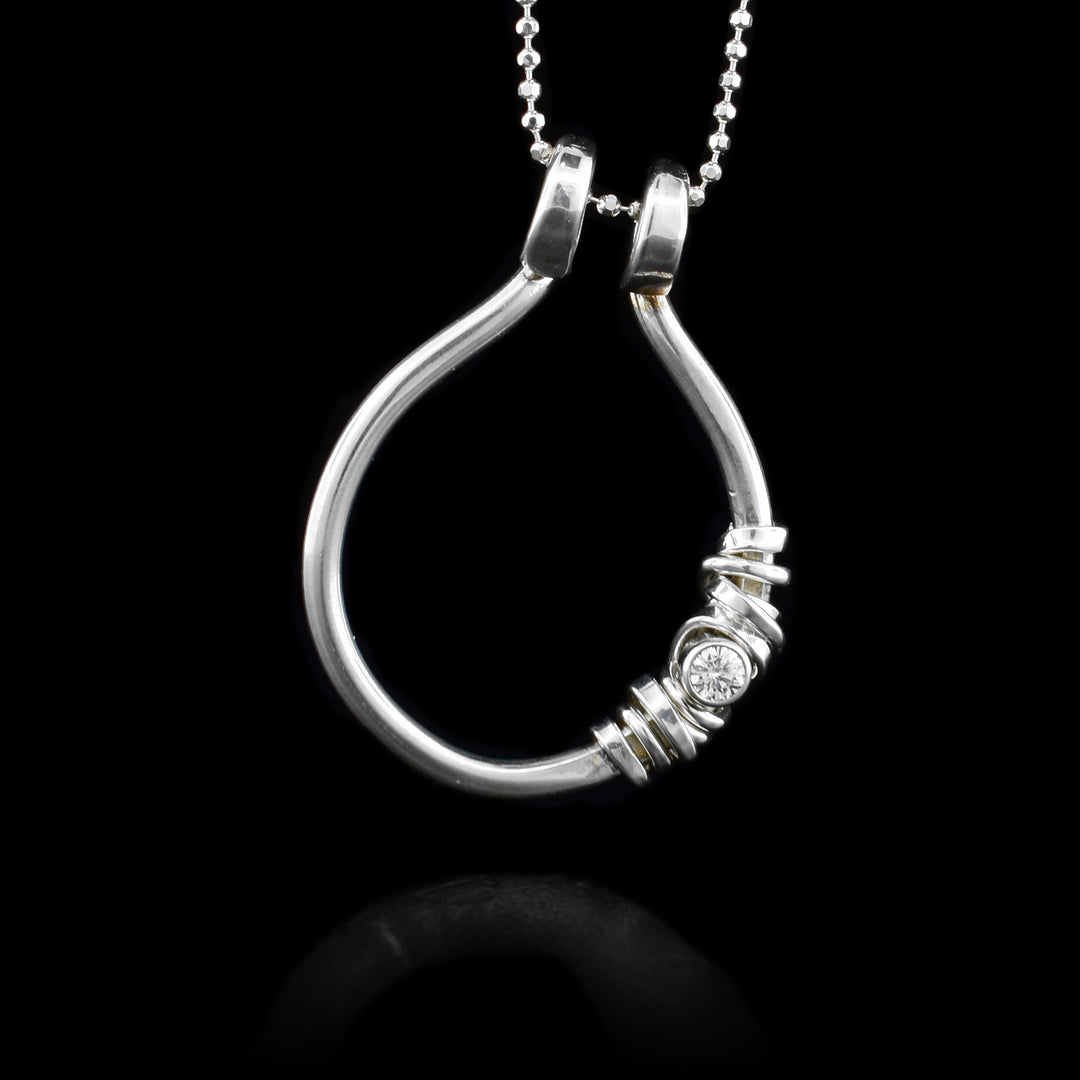 This cubic zirconia pendant is made from sterling silver and has an open hoop pendant with silver wrapping around a cubic zirconia gemstone.
