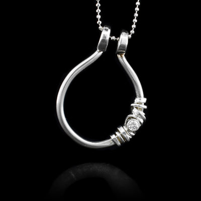 This cubic zirconia pendant is made from sterling silver and has an open hoop pendant with silver wrapping around a cubic zirconia gemstone.