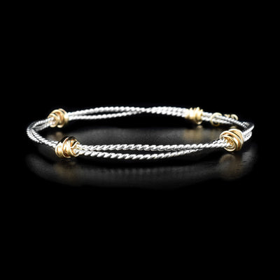 This bangle bracelet is made out of two sterling silver coils that are attached together with four areas of gold fill wrapped around the coils.