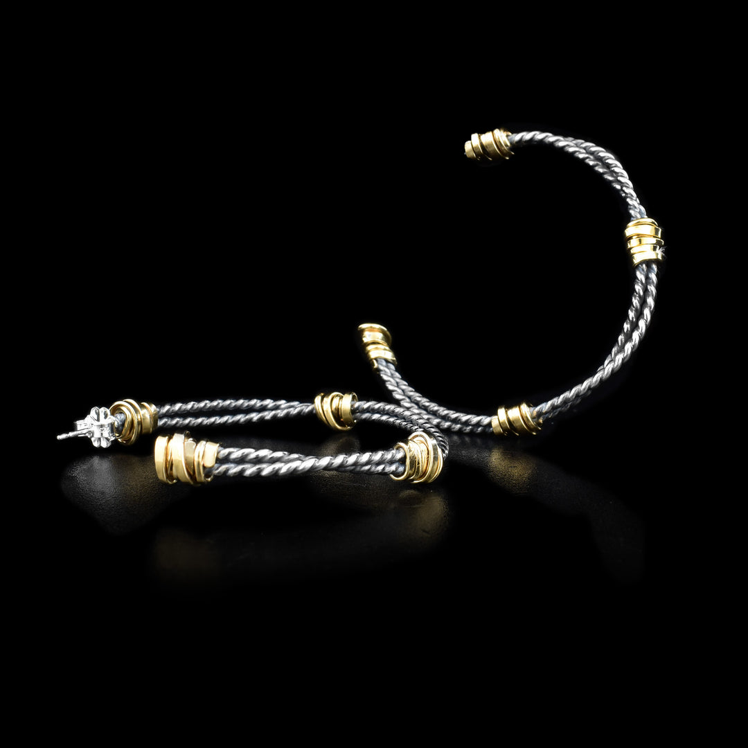 These sterling silver, coil hoop earrings are made of two coils that are held together by gold fill wrapped around them. The silver hoops have a darkened look to them.