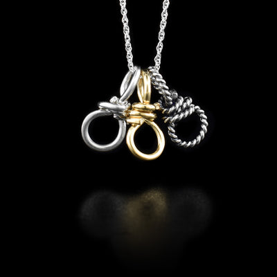 This silver and gold charm necklace is made from sterling silver and gold fill. There are three small, coil pendants on the chain