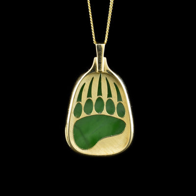 A 14K gold pendant that has a layer of gold on top with a jade stone underneath. The layer of gold has a bear print cut out, so the jade is visible underneath.
