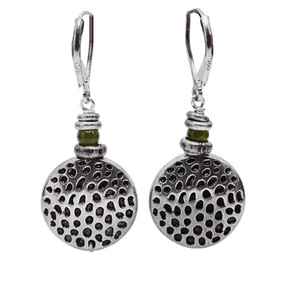 These sterling silver dangle earrings have large, circle hangs with textured dimples across the surface of them. There are jade balls above the hangs and below the hooks.