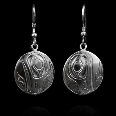 These sterling silver dangle earrings have circle shaped hangs with depictions of the Raven carved into the surface of them.