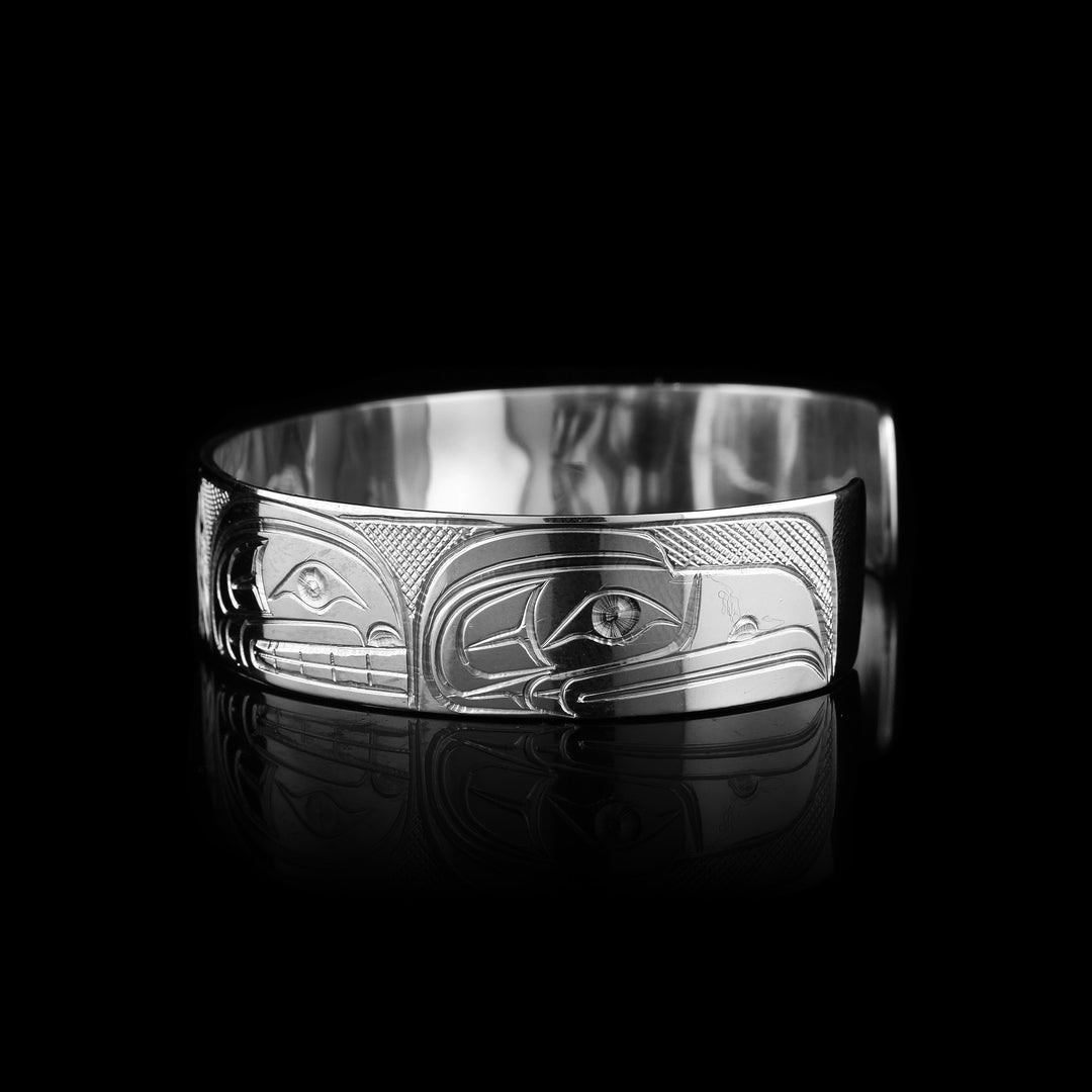 Discover authentic Indigenous wearable art by Travis Henry. This sterling silver bracelet is hand-carved with powerful symbols: the Sasquatch, Eagle, Raven, and Orca.