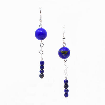 For both earrings, round bead of lapis at top. Below, silver hearts interlock, leading down to four stacked smaller round lapis beads. Metal is sterling silver.
