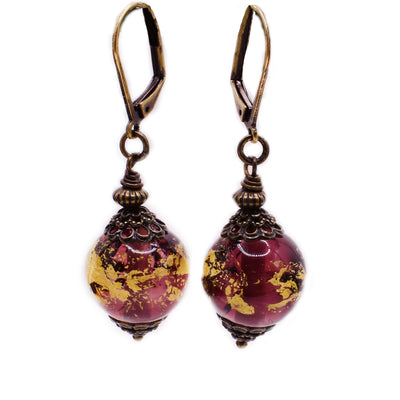 Brass dangle earrings featuring purple and gold handmade lampworked glass beads.