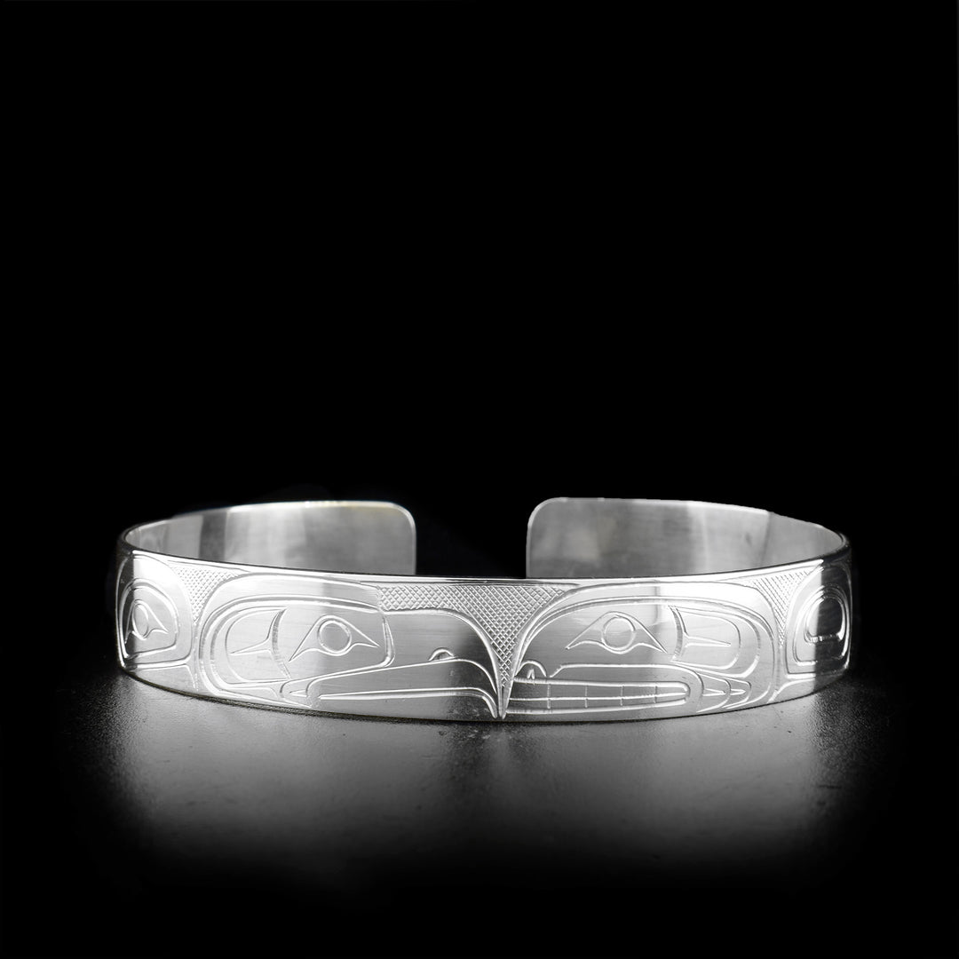 Sterling silver cuff bracelet featuring eagle and orca facing each other.