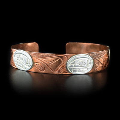 Copper bracelet features pattern of orcas swimming against cross-hatching background. Orcas have sterling silver heads. Hand-carved by Kwakwaka’wakw artist Norman Seaweed.