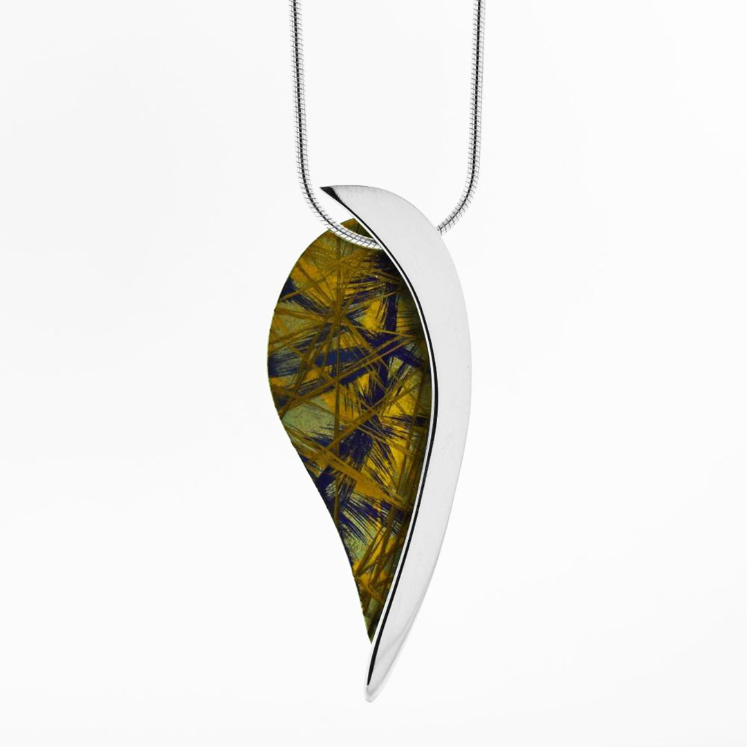This titanium pendant necklace is made from sterling silver and anodized titanium with an upside down teardrop shape. Half the pendant is made from anodized titanium and features yellow and purple designs; the other half is silver.