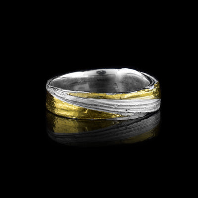 This thin silver band ring is made from sterling silver and has flowing designs on the surface of it. The piece is made by casting metal into wax so it mimics the appearance of its wax mold. There are keum boo gold highlights on the band around one of the strips of sterling silver.