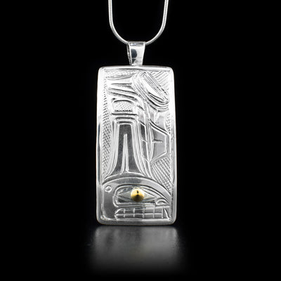 Pendant is sterling silver and features an orca. 14K yellow gold in eye. Cross-hatching background.