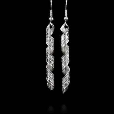 Both sterling silver earrings are a long rectangle, featuring a wolf, twisted into a spiral. By Coast Salish artist Gilbert Pat.