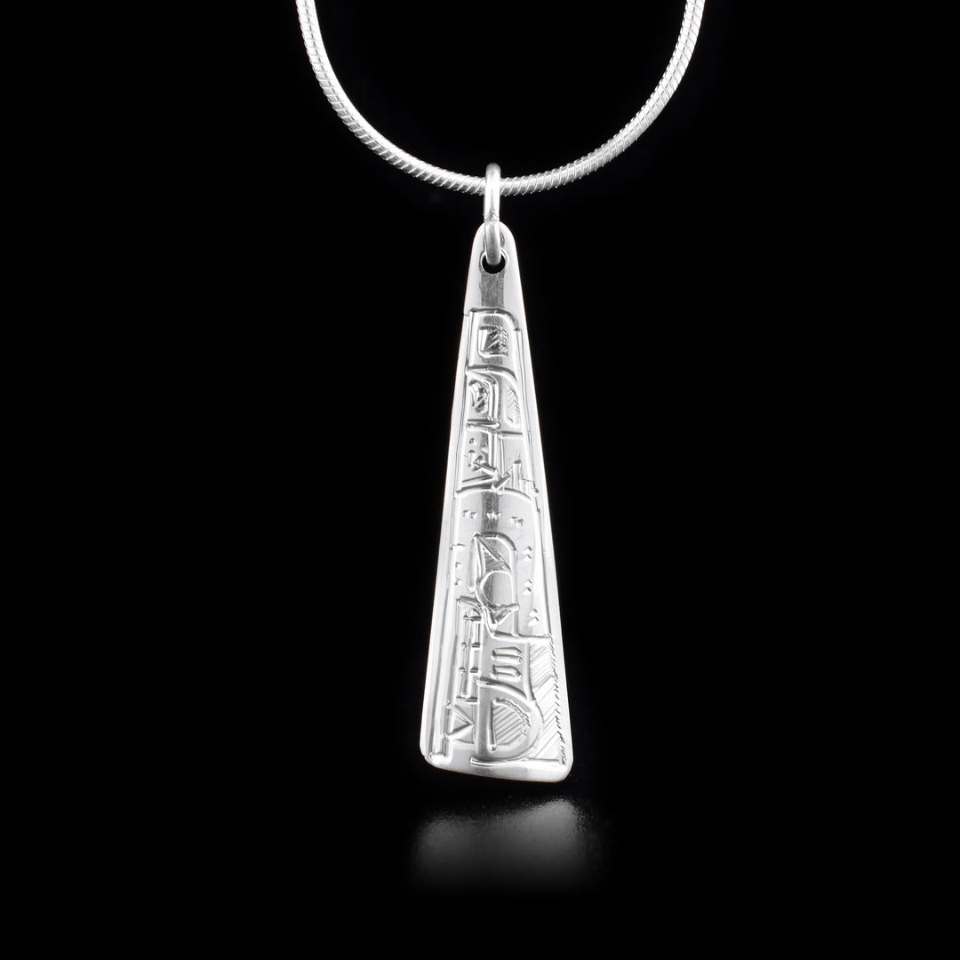 This Wolf pendant is made from sterling silver and is long and triangular. There is a depiction of the Wolf carved into the surface of the pendant.