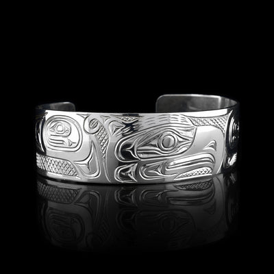 This Thunderbird bracelet cuff has been made using sterling silver and has a single, wide band with a gap in the back. The Thunderbird's head is carved into the center of the piece in a side profile and takes up the width of the band. Its two wings are depicted around it on the rest of the band. There are feather details made into the wings and the head as well as cross hatching patterns in the background of this piece.