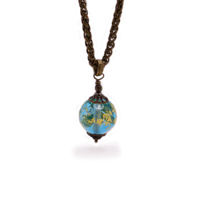 Brass pendant necklace featuring round, petite, blue handmade lampworked glass bead. Bead is clear and has 23K gold leaf inside. By Wendy Pierson.
