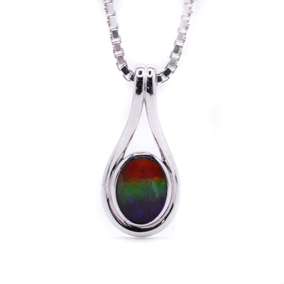 Polished, oval ammolite set in sterling silver. Pendant has teardrop shape and minimalist design. By Enchanted Designs.