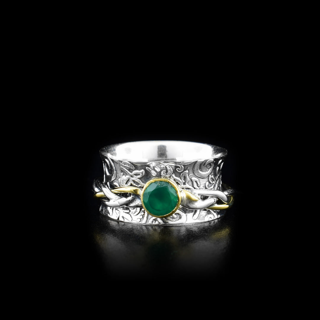 This gorgeous spinner ring is made form sterling silver, brass and green onyx gemstone. There is a wide, silver band with spiral designs made on the surface of it and a braided, silver brass ring over top of the band. The braided piece made from wires can spin around the band and the gemstone is held in brass on the spinning piece.