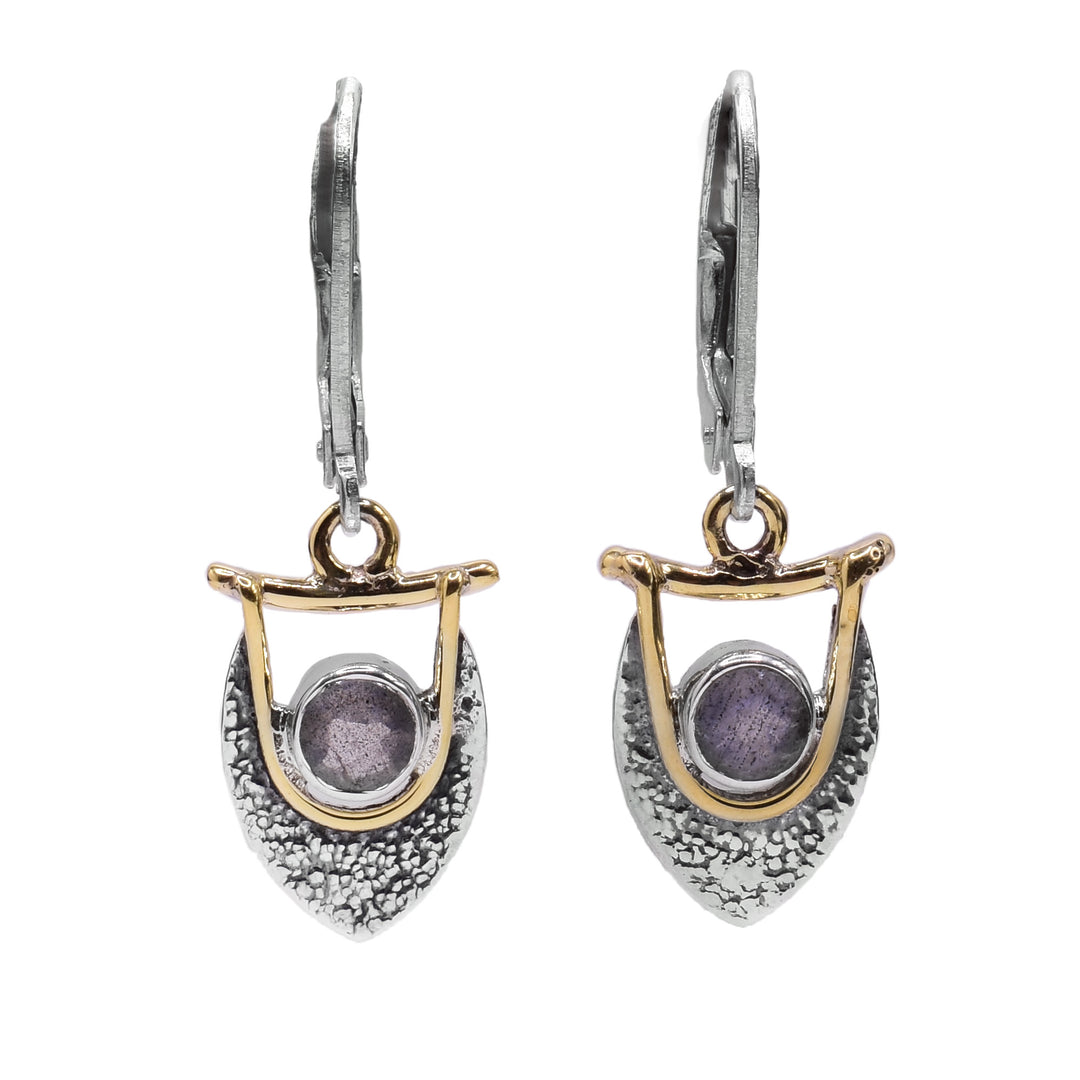 These labradorite earrings are made from sterling silver, brass and labradorite gemstones. The hangs have a teardrop shaped, textured silver piece with labradorite gems held at the top of them. There is brass wire wrapped around the gems and connect to the hooks.