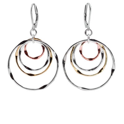 These large hoop earrings feature a combination of brass, copper and sterling silver hoops that start large and gradually shrink. The hoops are dangling from the hooks.