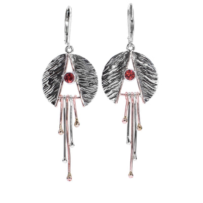 These garnet dangle earrings are made from sterling silver, copper and garnet gemstone. There is a textured, silver circle that is cut in half to form a trtiangle shaped cutout in them. There are garnet gems held in the center of the cutouts on copper rods dangling below them.