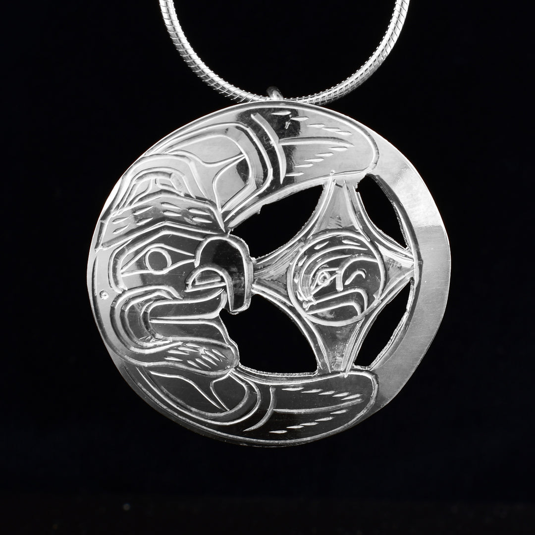 This circular sterling silver pendant is artfully cut into the shape of a crescent moon and star. Within the curve of the moon, a hand-carved moon face adds a touch of mystique, while the star holds the finely detailed face of an eagle.