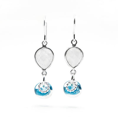 Faceted, downward teardrop-shaped moonstone dangles from hooks. Blue and clear glass adornment and silver ring adornment dangle below gemstone. All metal is sterling silver.