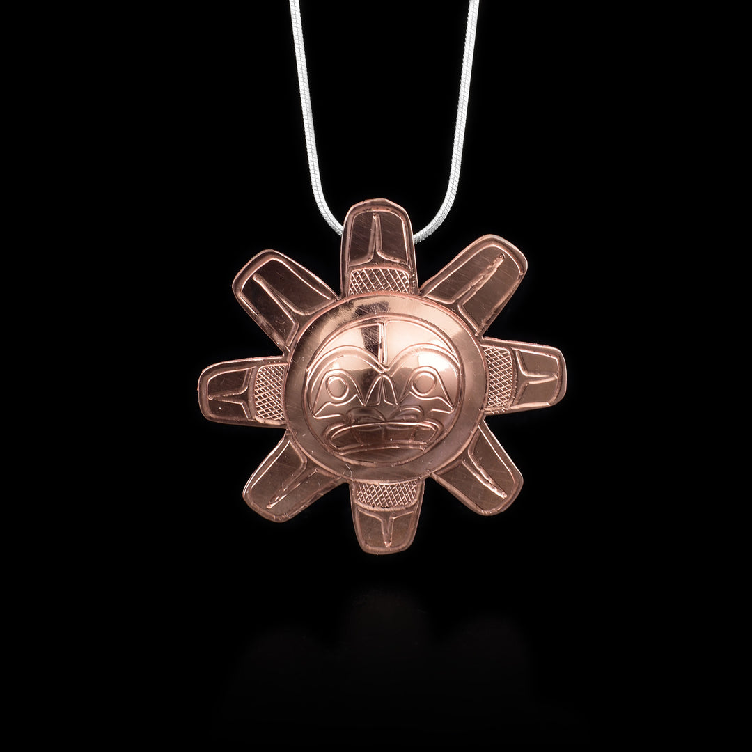 This large, Sun pendant is made from copper. The pendant is shaped like and has carvings on the surface of it that depict the Sun.