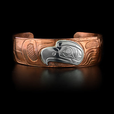 This copper cuff bracelet has carvings that depict the Raven. The head of the Eagle is made from sterling silver.