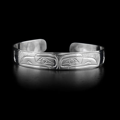 This sterling silver cuff bracelet has two depictions of the Raven carved into it. Their heads meet at the top of the bracelet. 