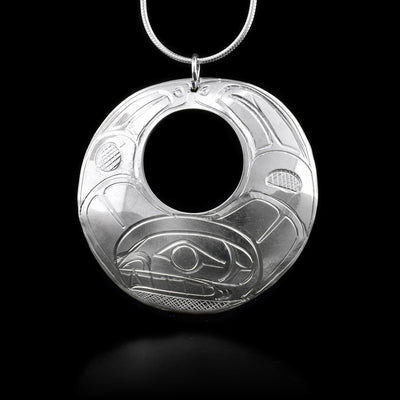 This sterling silver pendant is a circle with a small circle cutout in the middle. There is a depiction of the Orca carved into the surface.