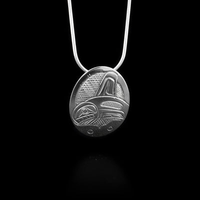 This sterling silver pendant is oval shaped and has a depiction of the Orca carved into the surface of it.