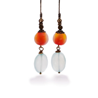 Long dangle earrings with round, translucent orangey handmade lampworked glass beads. Faceted oval blue chalcedony dangles below.