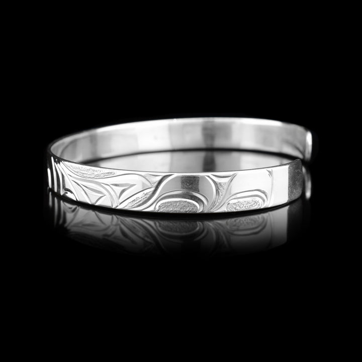 Right side of the cuff bracelet depicts carvings representing the dorsal fin of the orca and more waves.